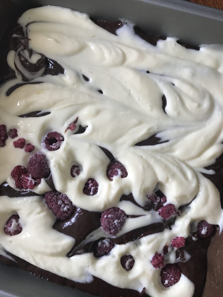 frozen raspberries added to half of the cheesecake brownie before baking
