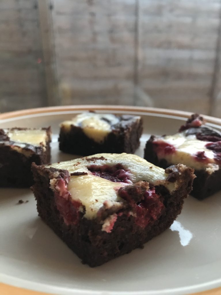 4 cut up brownies. The two nearest are raspberry cheesecake brownies and the two further away are vanilla cheesecake brownies